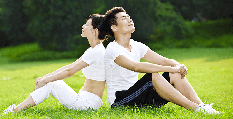 couple seated back to back in a field