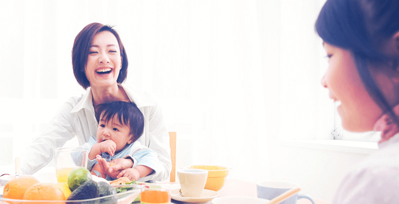 laughing mom holding baby at the dining table